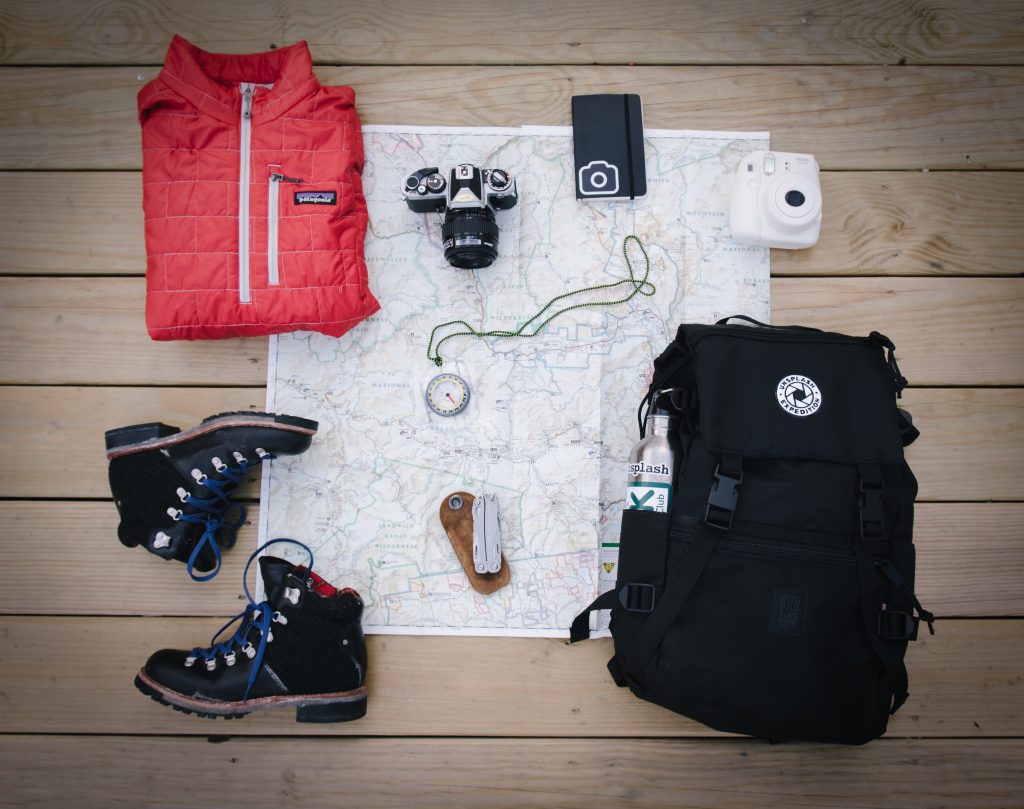 photo de l'interieur d'une valise avec des chaussures de marches, un kway et un appareil photo -Retrouvez nos conseils sur le blog de New York Off Road en fonction des saisons, visites guidées en français de la Grosse Pomme