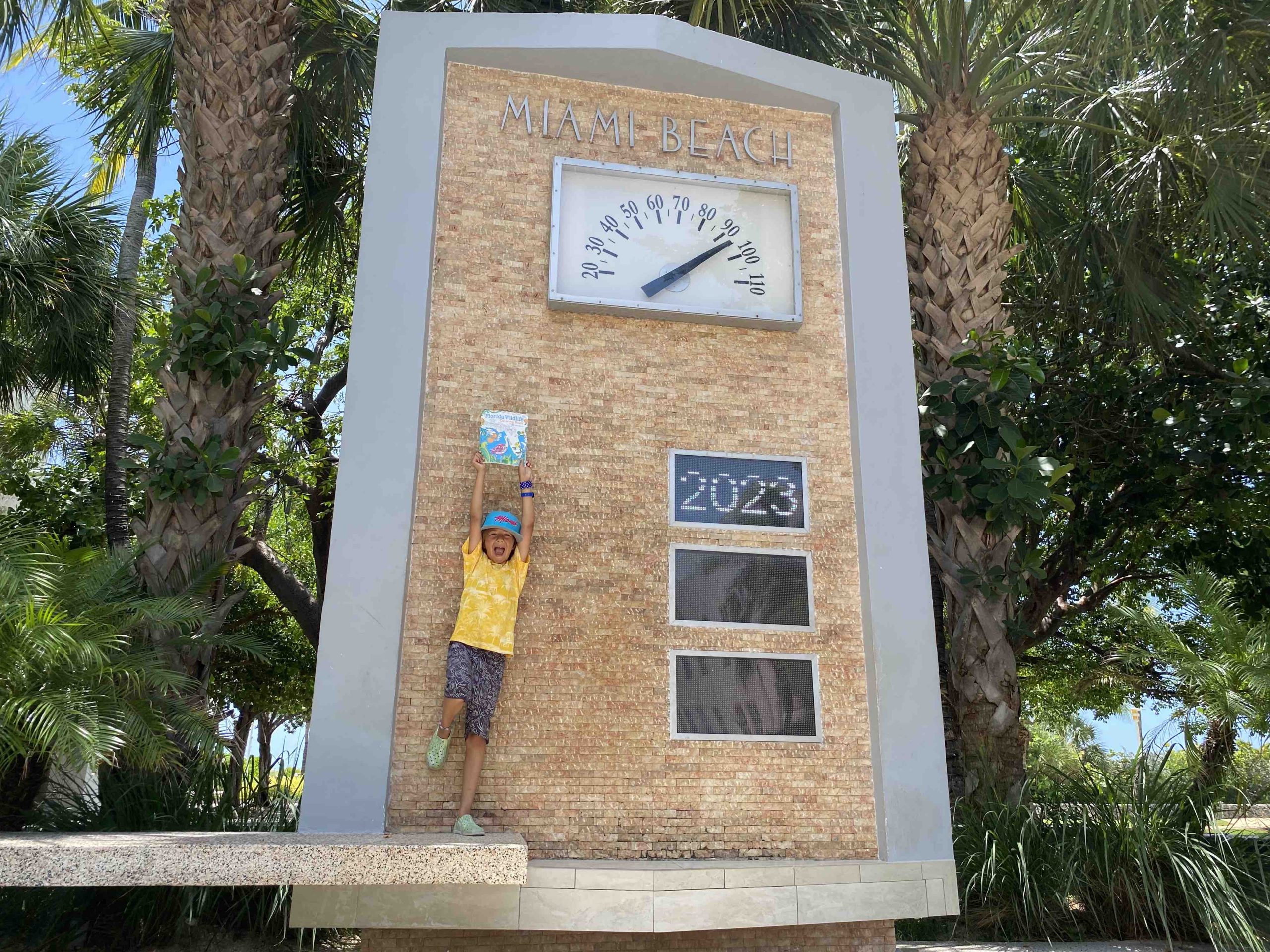 enfant et livret de coloriage cadeau devant l'horloge de Miami Beach